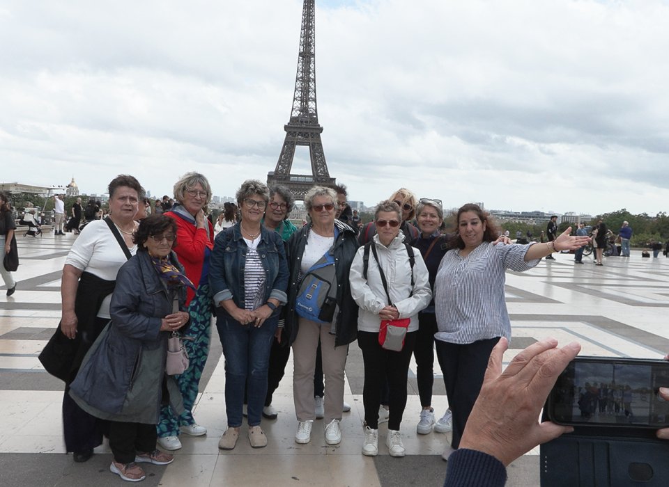 un groupe de vacanciers aidé par le secours catholique devant la tour effeil à paris